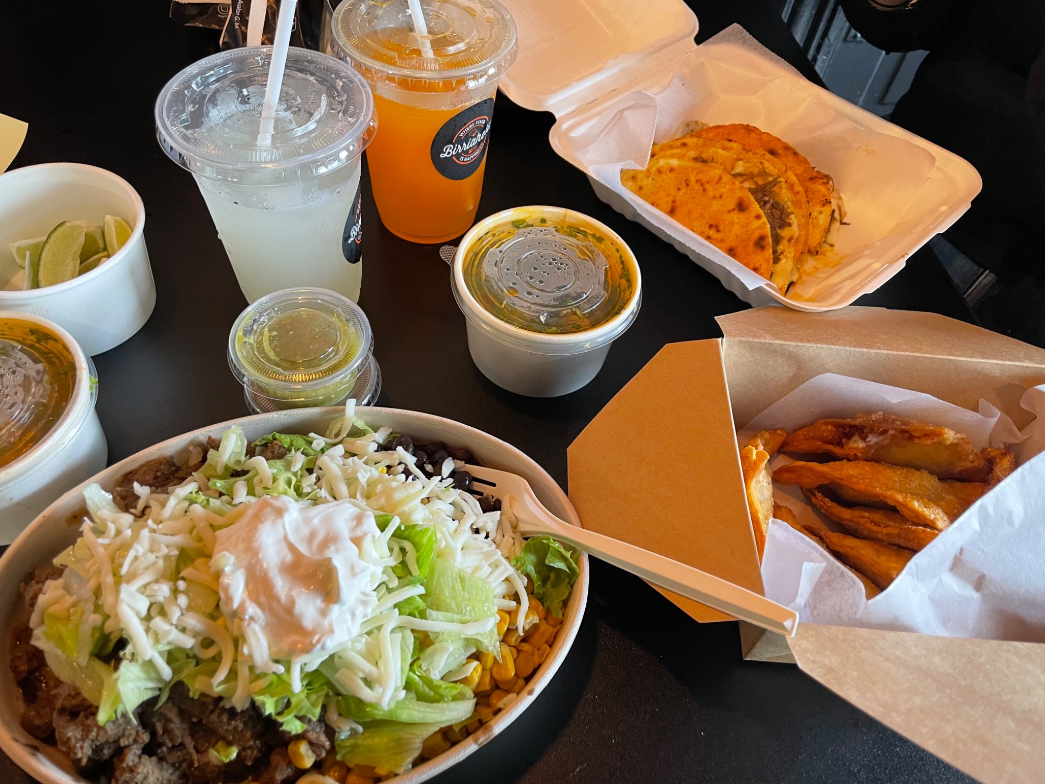 Birriaholic table spread with tacos, a build-your-own bowl, fried sides, sauces and drinks